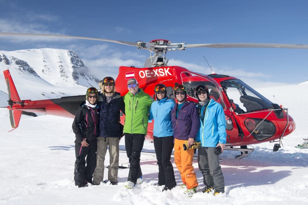 six_people_standing_in_front_of_red_helicopter